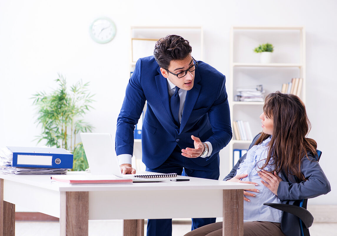 Pregnant woman struggling in the office and getting colleague help